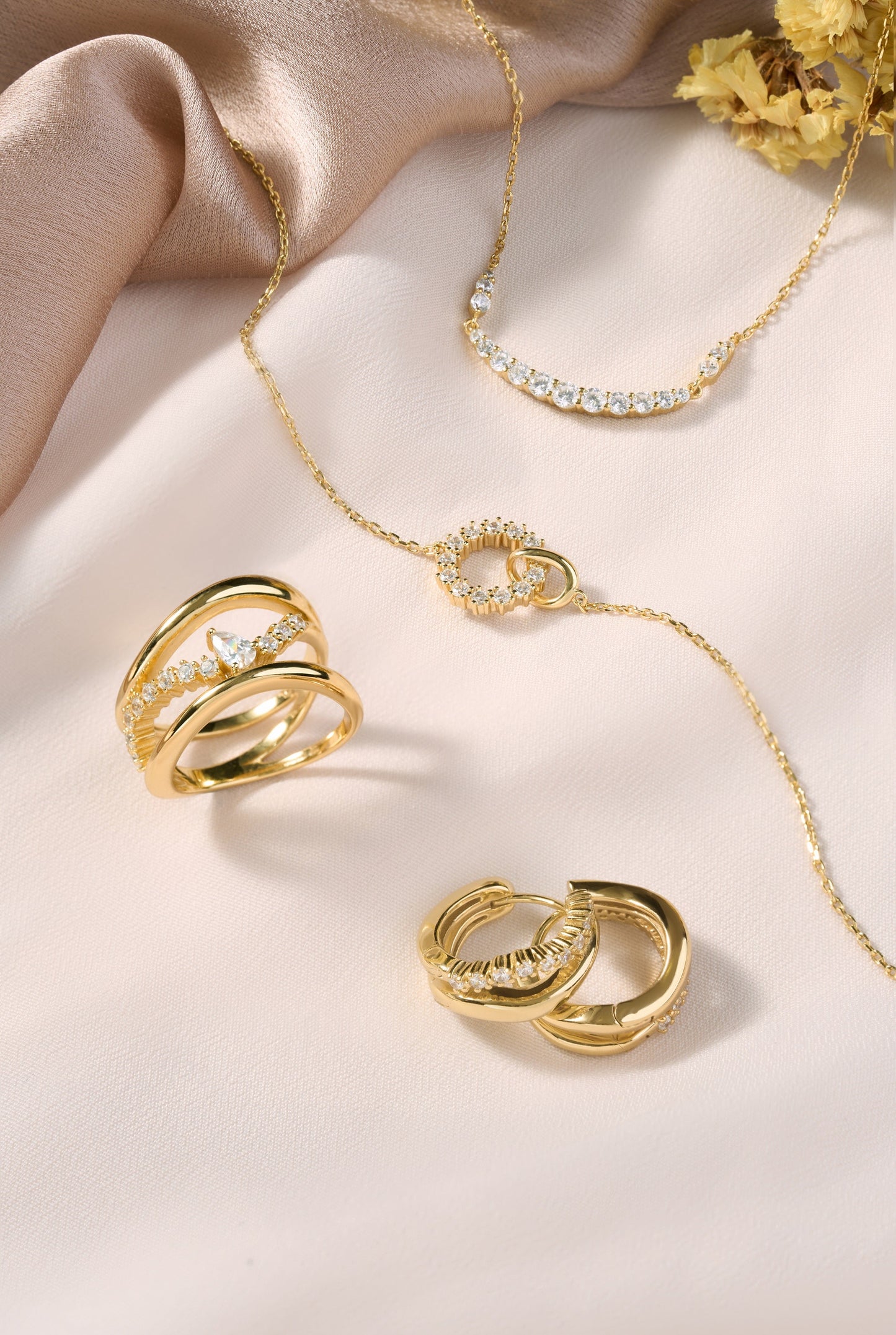 Elegant gold jewelry set featuring interlocking circle charm necklace, delicate layering chains, and sparkling statement ring