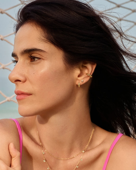 Small gold dome huggie earrings worn on ear