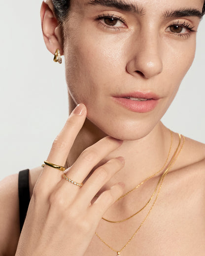 Close-up of a minimalist gold bezel set ring worn on finger