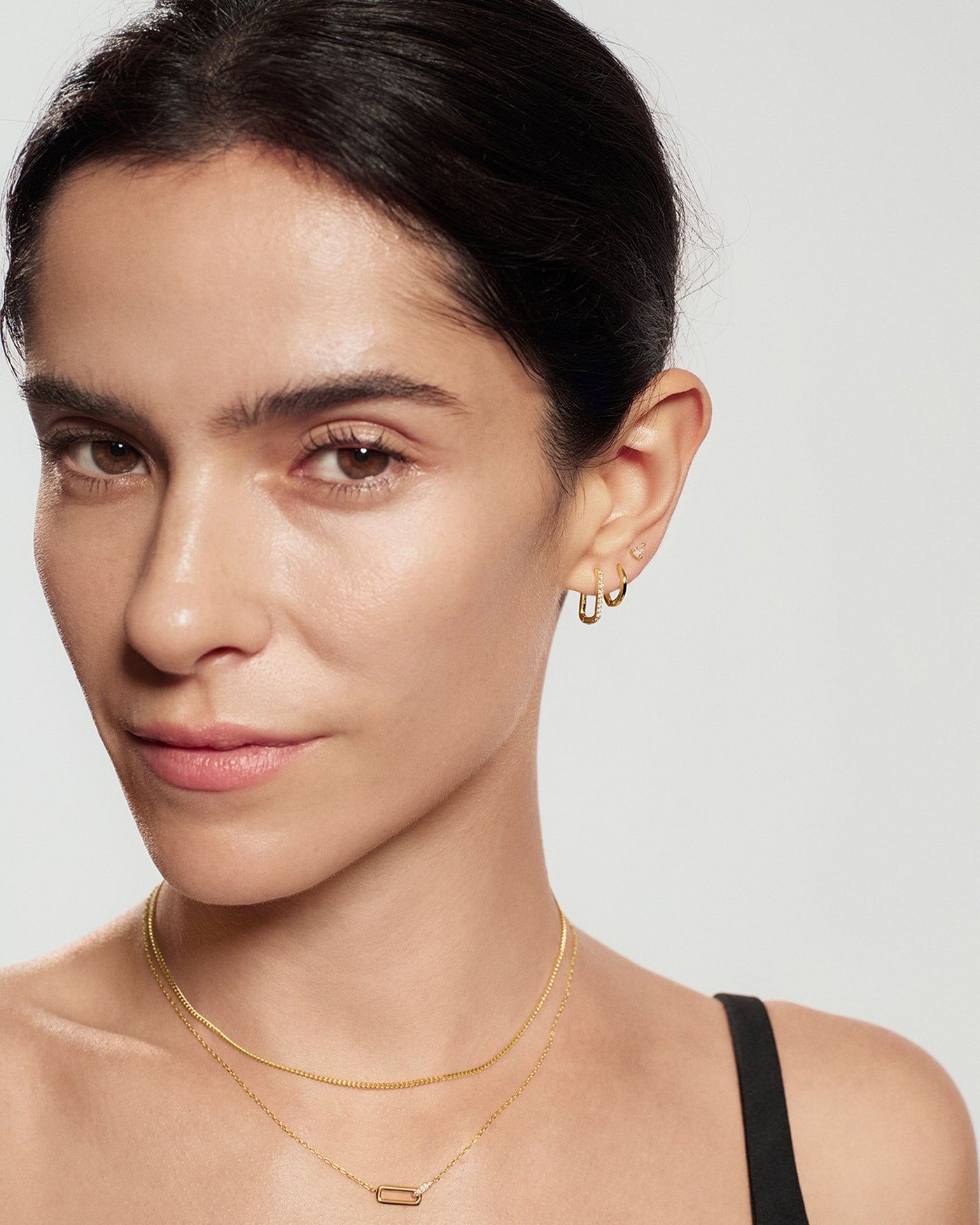 Close-up of a gold geometric interlock charm necklace worn on neckline
