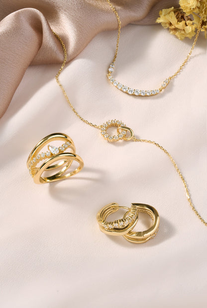 Elegant gold jewelry set featuring interlocking circle charm necklace, delicate layering chains, and sparkling statement ring